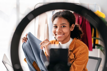 Woman designer entrepreneur showing clothes product on live online social media streaming and...