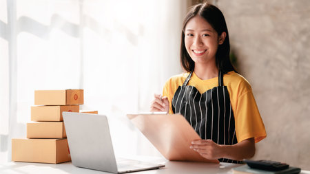 Small business parcel delivery concept, Female entrepreneur writing information on clipboard while packing product to shipment delivery for client and working about shopping online sales business.の写真素材