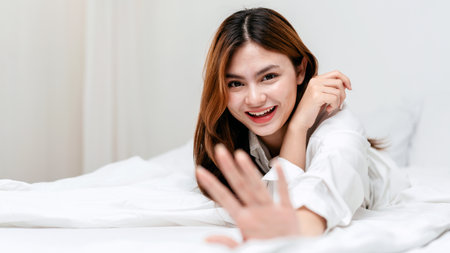 Activity at home leisure lifestyle concept, Young woman in clothes casual lying on comfy bed to smiling and looking on camera while leisure with lifestyle in bedroom at home.の写真素材