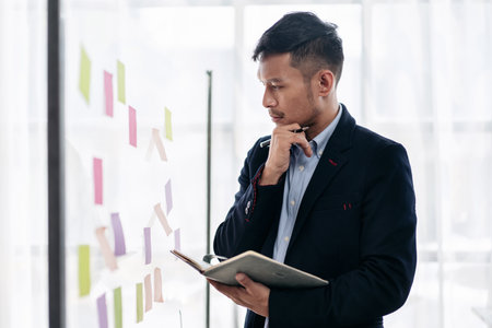 Business planning with share idea concept, Businessman working and writing information in notes on the glass wall and thinking to analysis about business planning in office.の写真素材
