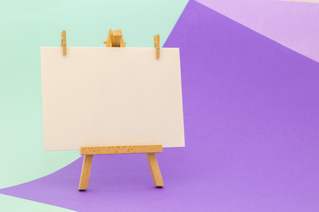 White paper on little easel on colorful violet and aquamarine background