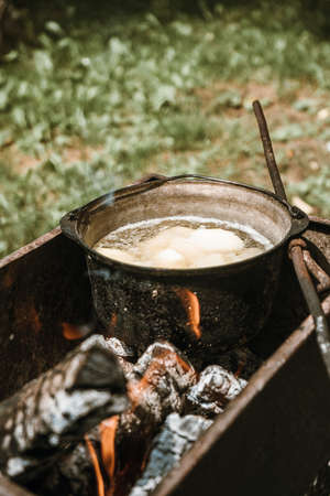 potatoes are boiled in a cauldron, green grass in the background, summer breakfast lunch dinner, food in nature.の写真素材