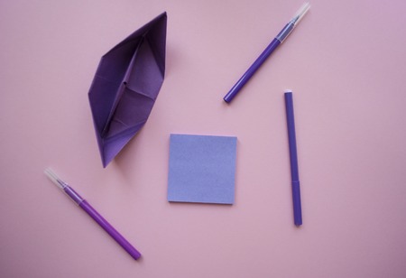 Paper ship, a notebook of violet color and markers on pastel violet background with text space.の写真素材