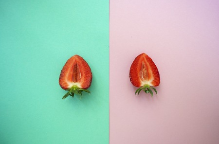 Halved red juicy strawberries on pink and turquoise background.の写真素材