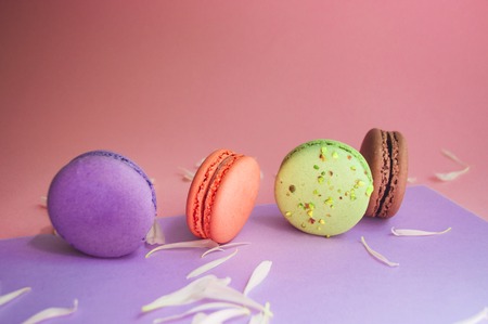 Macarons of different color on multicolored background.