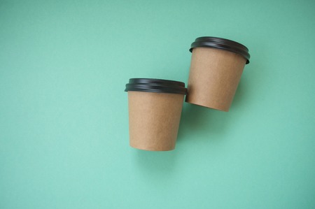 Two paper cups for hot drinks on blue background with text space.
