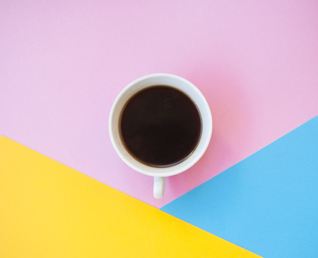 A cup of fresh black coffee on pink, blue and yellow background with text space.の写真素材
