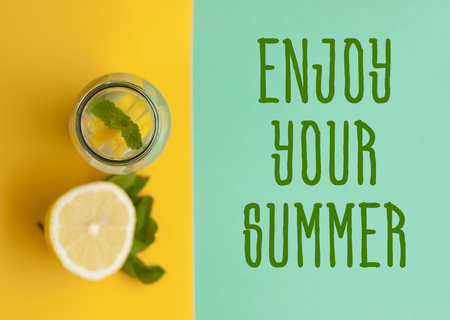 Top view of mason jar glass of lemonade or mojito with lemons and mint on bright yellow and turquoise background with text space.の写真素材
