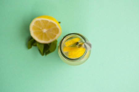 Top view of mason jar glass of lemonade or mojito with lemons and mint on turquoise background.の写真素材