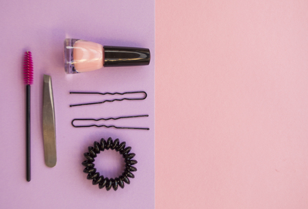 Set of cosmetics and hair accessories on pink and violet background with text space.の写真素材