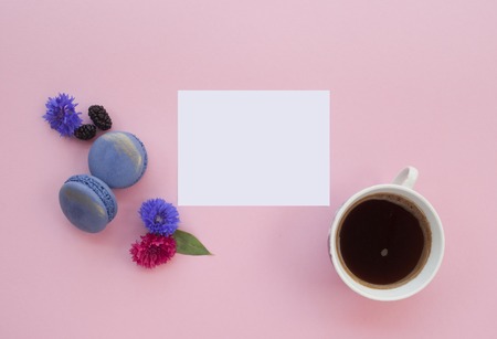 Cup of coffee and macaroons on pink background.