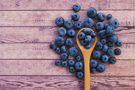 Fresh and juicy blueberries in a wooden spoon on wooden table with copyspace. Healthy food concept.の写真素材