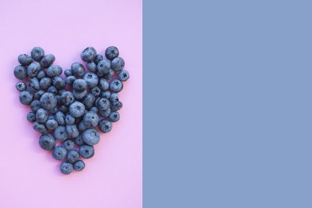 Delicious freshly picked bluberry in a form of heart on purple and pink background with copyspace. Healthy food concept.の写真素材