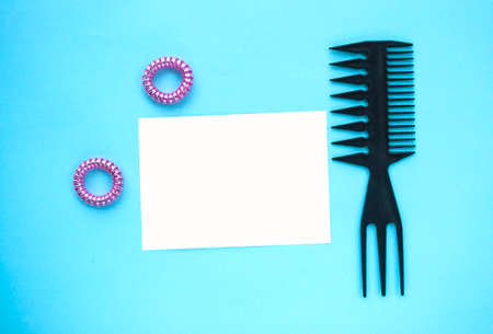 Black plastic comb and two pink scrunchies on blue background.
