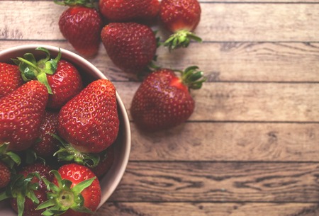 Top of view fresh strawberry in a pink bowl on wooden board.の写真素材