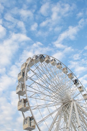Ferris wheel over blue cloudy sky in a fun park.の写真素材