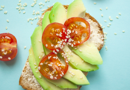 Fla lay of delicious toasts with sliced avocado, tomatoes and sesamum seeds. Healthy food concept.