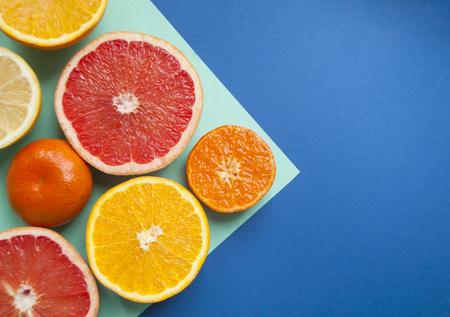 Fresh ripe juicy grapefruit, lemon, orange and tangerine on blue and turquoise background with...