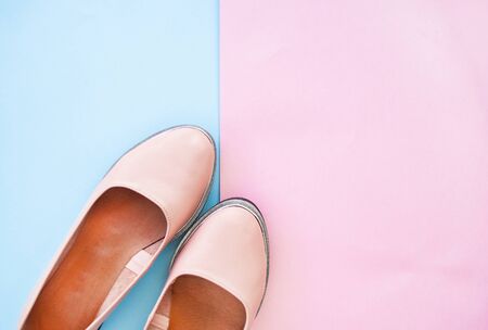 Beautiful minimalistic pink color female shoes on dark blue and pastel pink background with copyspace.の写真素材