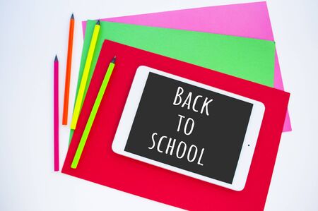 Colorful paper, neon pencils and tablet on white background with copyspace. Flat lay style. Back to school concept.の写真素材