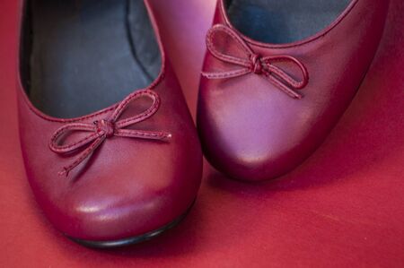 Close up of stylish female flat shoes in dark red color on dark red background. Beauty and fashion concept.の写真素材