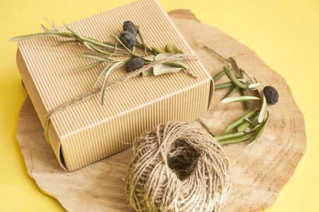 Zero waste gift ideas. Giftbox bowed with cord and olive branch on wooden background and copyspace.の写真素材