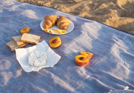 Beautiful summer picnic on the beach by the sea at a sunrise. Organic fresh fruits and cheese on...