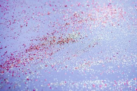 Blurred background of colorful confetti, sparkles on bright purple background. Festive background.