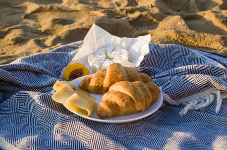 Beautiful summer picnic on the beach by the sea at a sunrise. Organic fresh fruits and cheese on linen blanket.の写真素材
