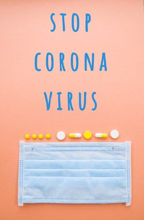 A syringe with a needle and a blue face mask on orange color background. Stop coronavirus concept. Protect yourself.の写真素材