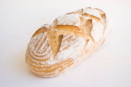 Freshly backed wholegrain bread covered with flour on white background. Food concept.の写真素材