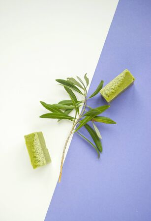 Flat lay of an olive branch, handmade olive soap bars on purple and white background.の写真素材