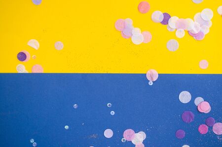 Colorful confetti, sparkles on bright yellow and classic blue background. Festive background.
