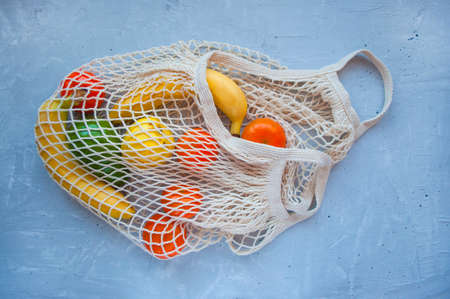 Eco bag with ripe fruits on grey background.