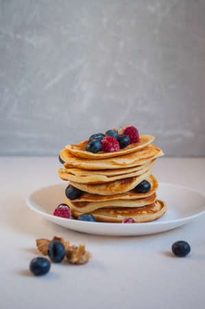 Freshly cooked delicious pancakes with honey, walnut, raspberries and blueberries for breakfast.の写真素材
