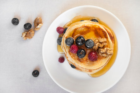 Freshly cooked delicious pancakes with honey, walnut, raspberries and blueberries for breakfast.の写真素材