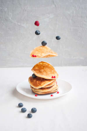 Flying freshly cooked pancakes and berries with honey, walnut for breakfast.