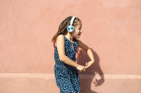 Cute little girl listening to music and dancing wearing headphones.の写真素材