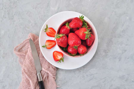Flat lay of fresh ripe sweet strawberries in a white bowl on a gray color background.の写真素材
