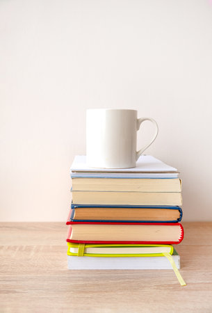 Stack of hardcover books with a white cup of coffee on the top.の写真素材