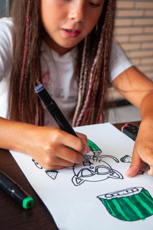 A happy little girl is drawing with markers.のeditorial素材