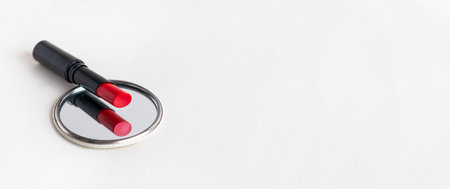 Beautiful red lipstick and a compact mirror on white background with copyspace. Professional makeup product.の写真素材
