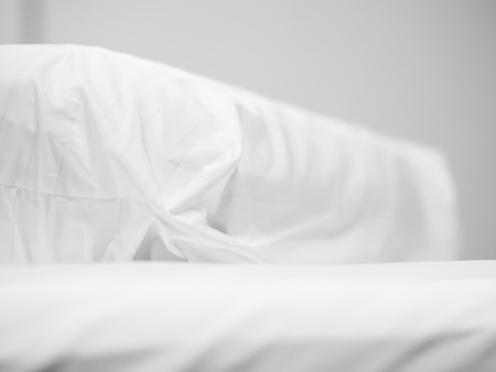 Closeup of white bolster on bed in bedroom.の写真素材