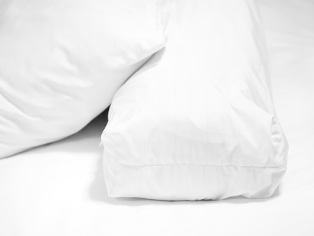 Closeup of white pillow and bolster on bed in bedroom.の写真素材