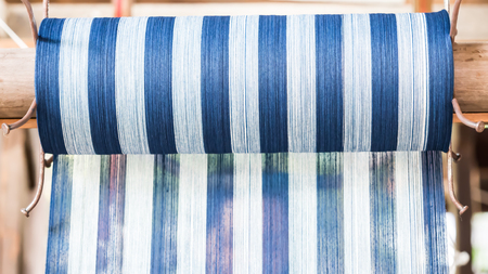 Closeup of white yarn, loom and silk roll for handwoven production.の写真素材