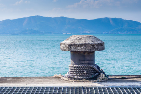 cement mooring bollard with ship ropes and seascape background.の写真素材