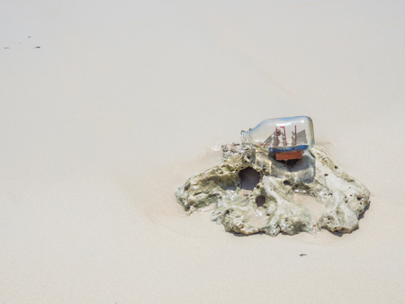 Ship in a bottle on a coral and sand on the beach.の写真素材