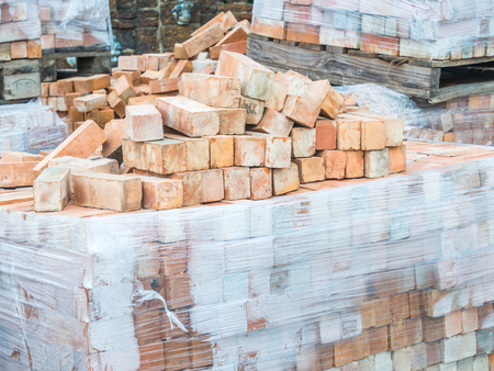 Stack of orange clay bricks at construction site.