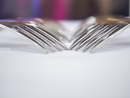 Closeup of forks on the white table with blurry background.