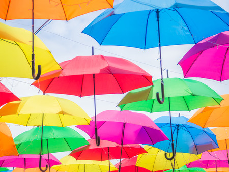 Multicolored umbrella pattern decorated with cloudy sky background.の写真素材